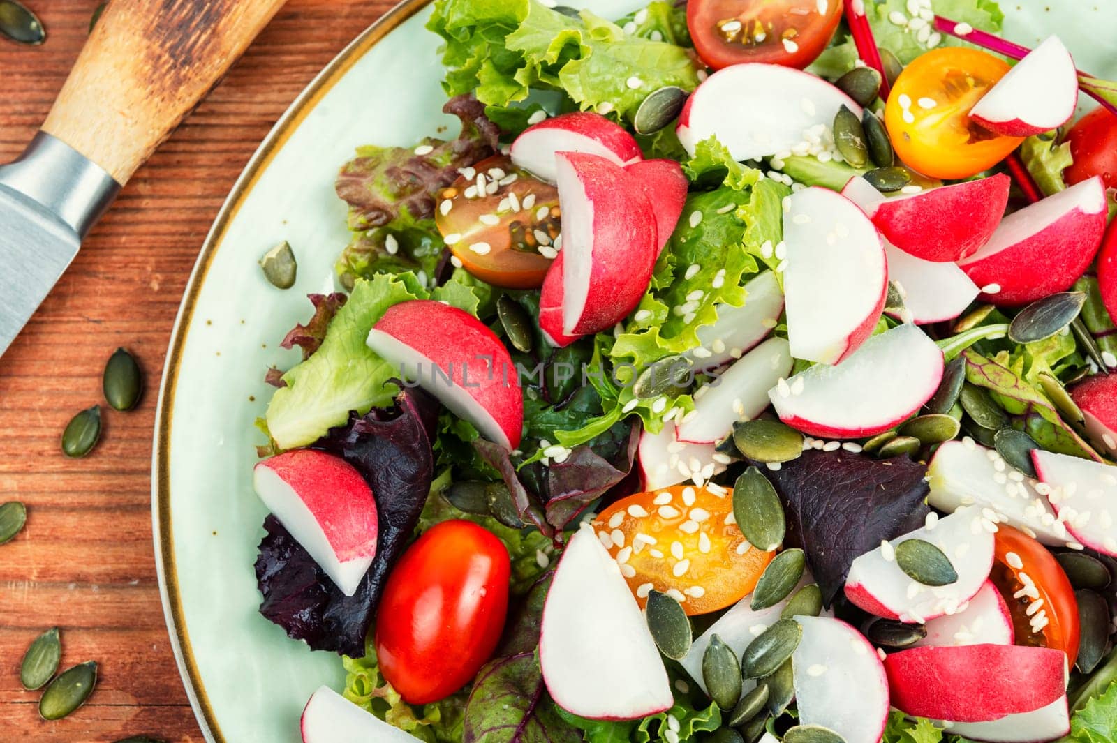 Tasty salad with radish, greens, tomato and sesame. Vegan recipe.
