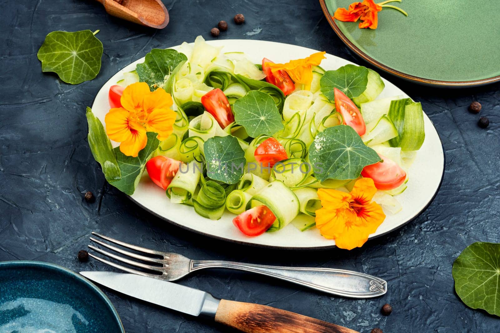 Rural salad with vegetables, nasturtium and dressing on wooden table.