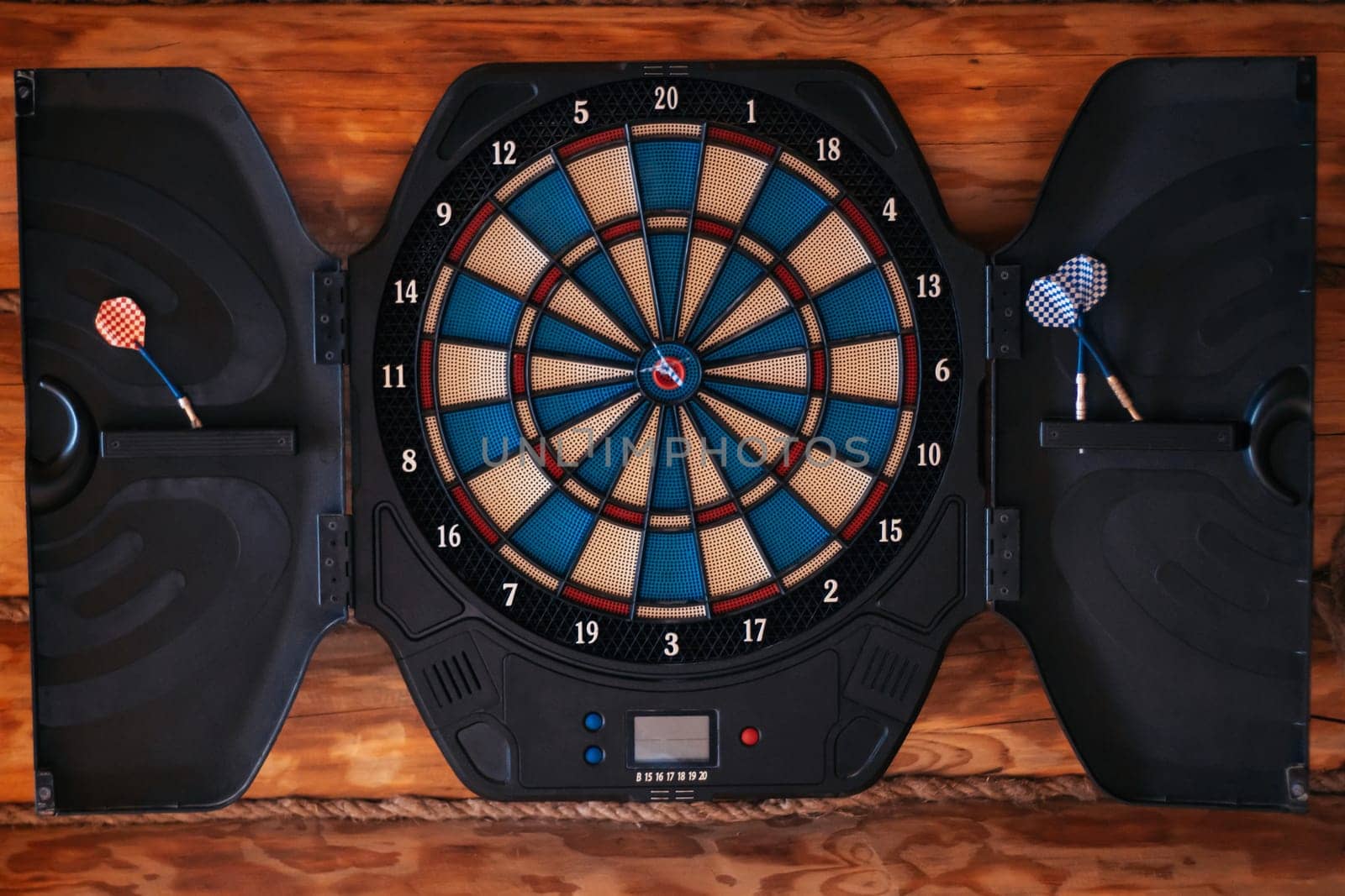 Bright multicolored dartboard hangs on wall. Close-up. Games and entertainment. Excitement and sport. Decorative elements. Design. Darts. Game board. Training and sports.