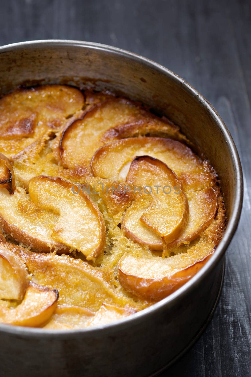 closeup of rustic apple cake in baking tin