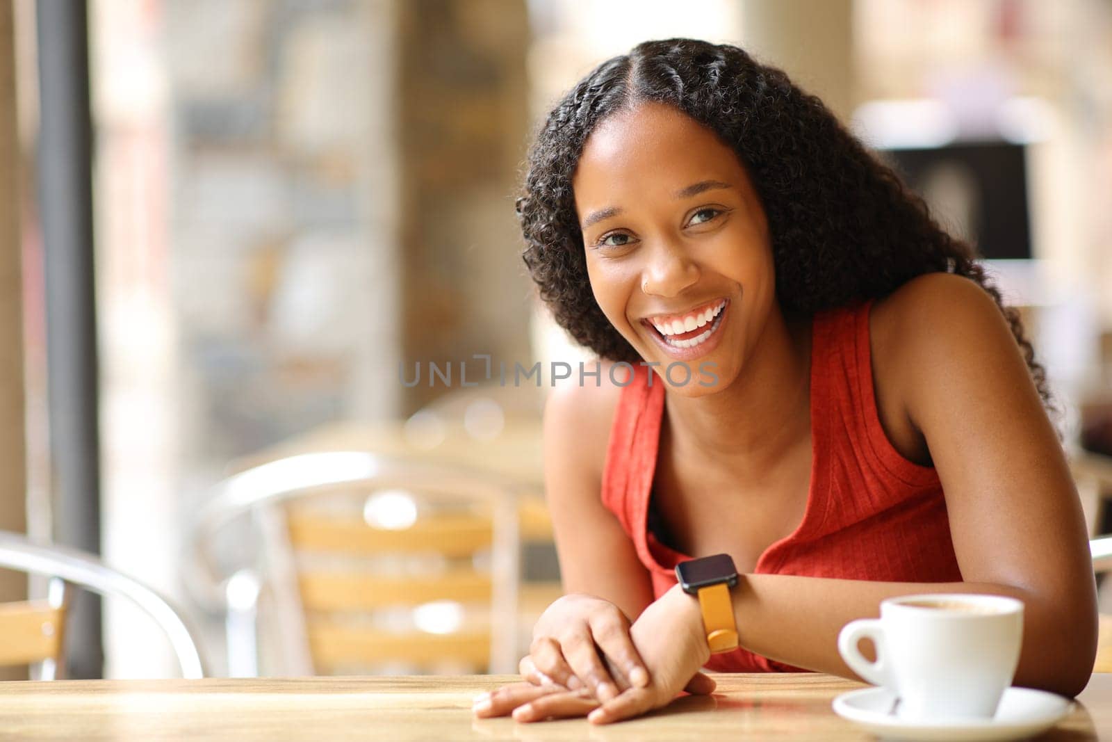 Happy black woman laughing looking at camera in a bar terrace