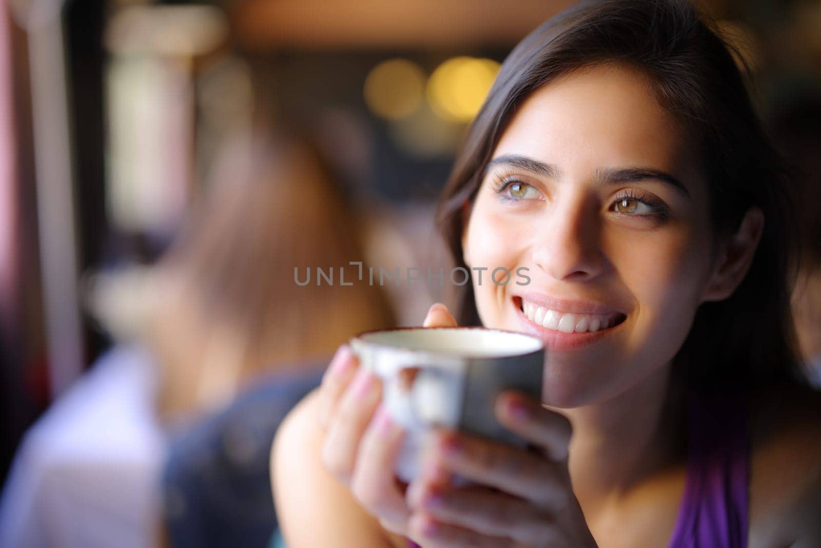 Happy dreamer dreaming drinking coffee in a restaurant interior