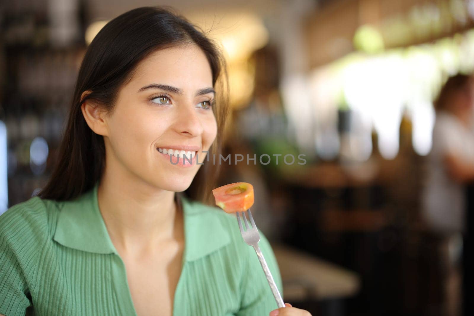 Happy customer eating tomato in a restaurant interior