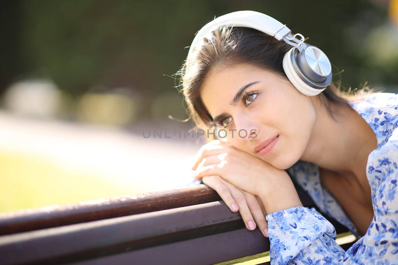 Pensive woman listening audio with headphone in a park