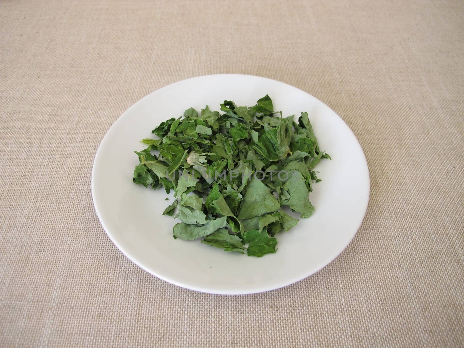 Dried garden nasturtium herbs on a white plate, Tropaeoli herba