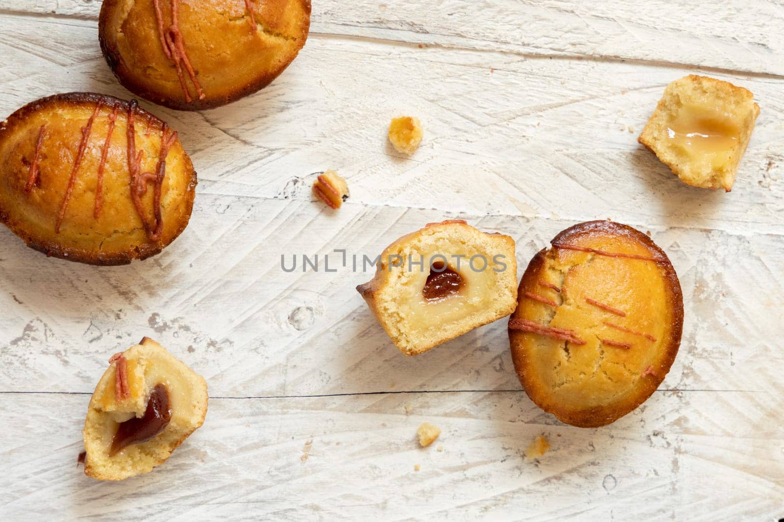Pasticciotto leccese pastry filled with egg custard cream and sour cherry jam. Whole and half pasticiotties on a white wooden talbe, typical apulian breakfast, top view