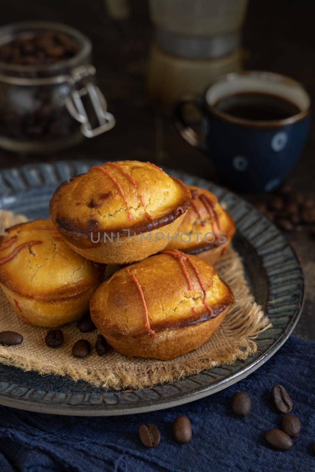Pasticciotto leccese pastries on a dark blue plate near coffe cup and moka on dark table, typical apulian breakfast, close up. Table decorated with coffee beans and napkin