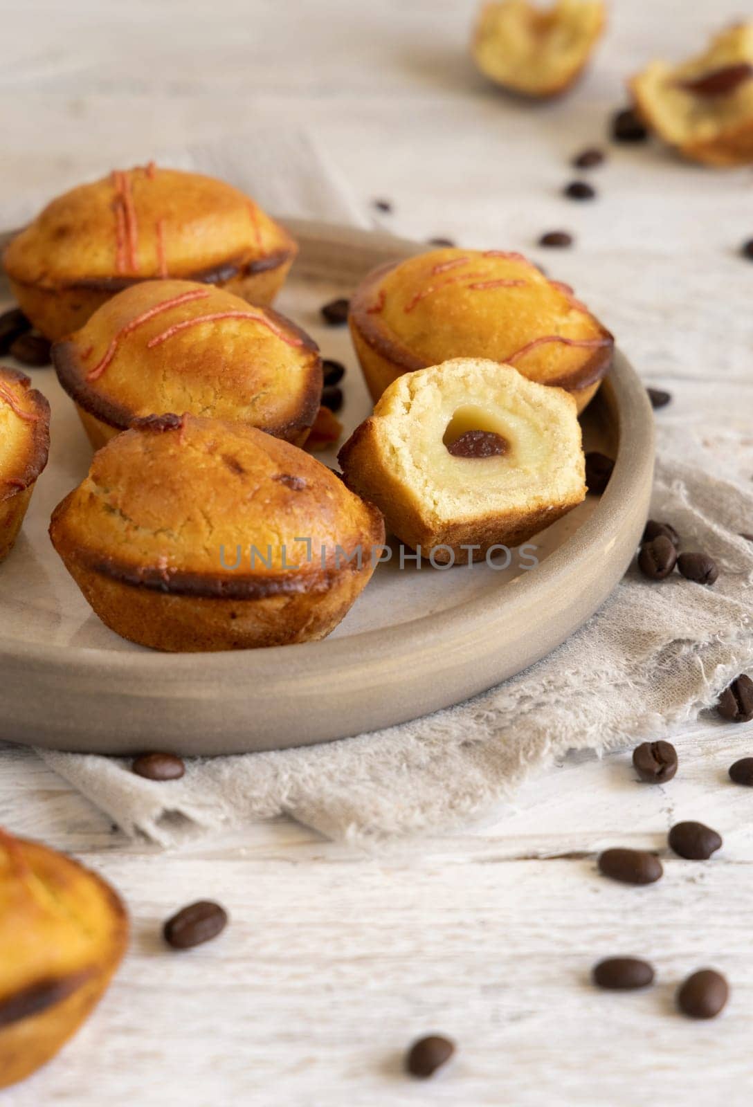 Pasticciotto leccese pastry filled with egg custard cream and sour cherry jam. Whole and half pasticiotties on a plate served for typical apulian breakfast, close up. Table decorated with coffee beans