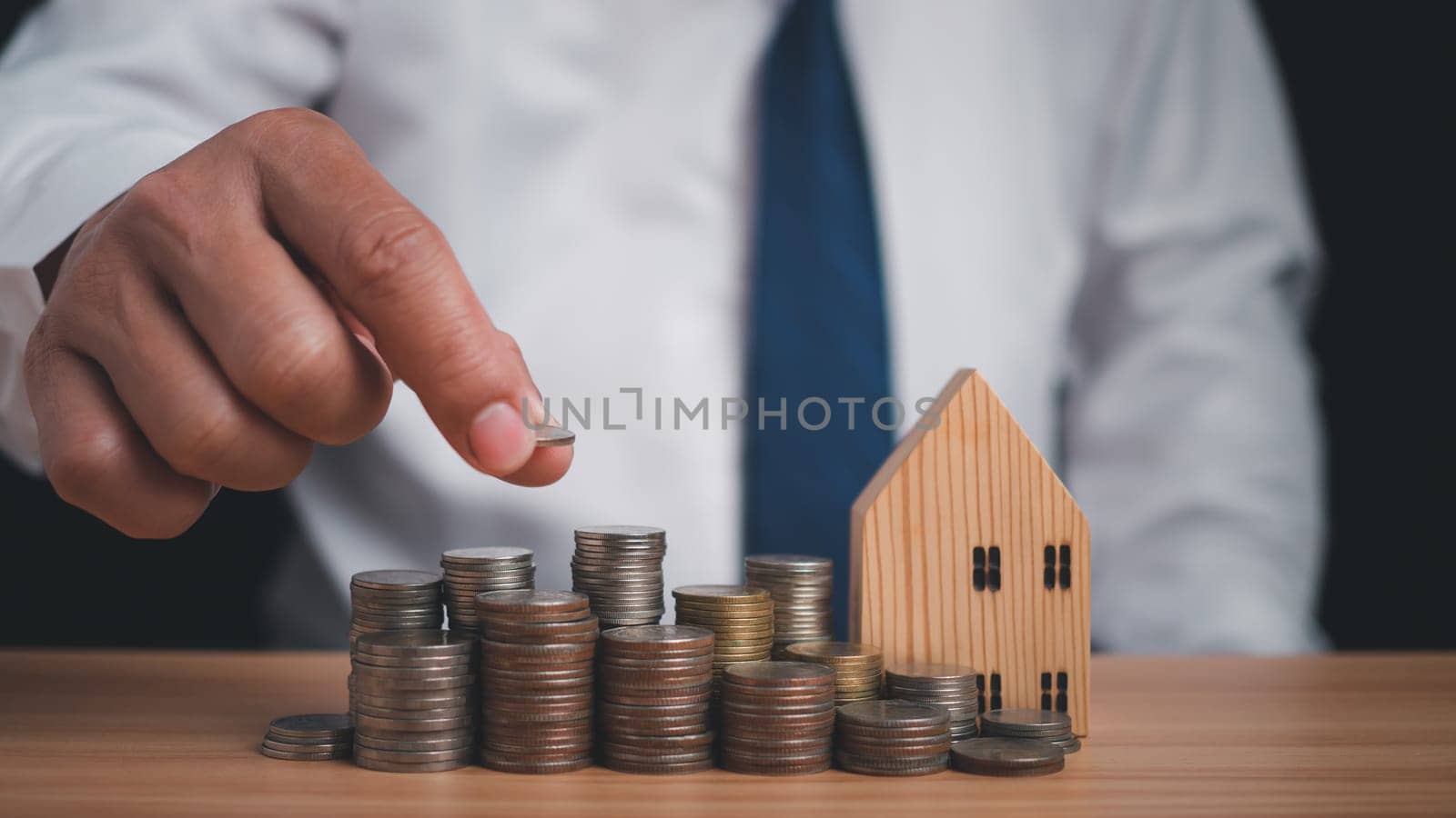 Human puts money on pile of coins. Ideas for investing and growing a business, maximizing profits from business, ideas for setting savings goals and setting goals for fixed deposits with banks.