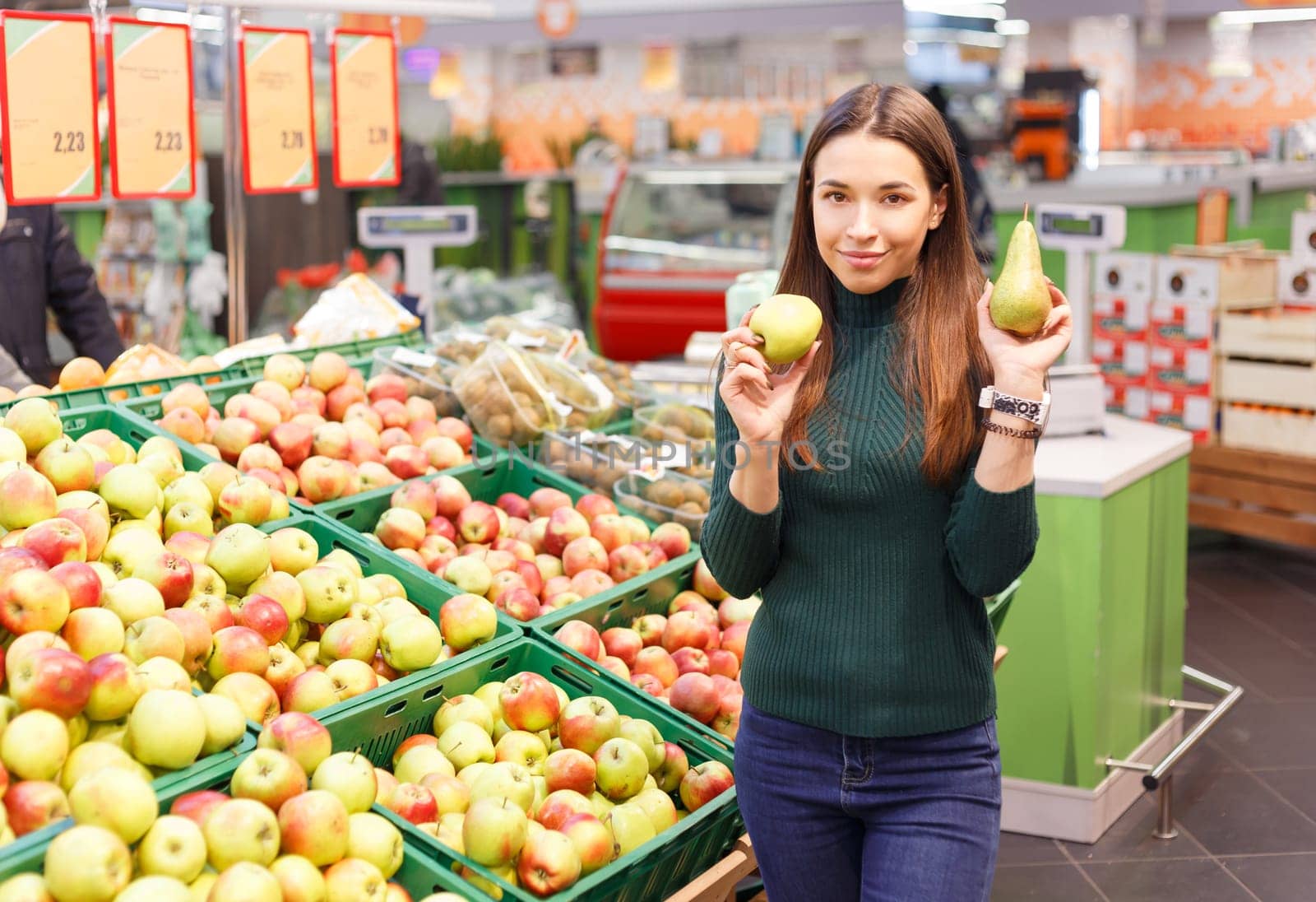 Pretty young woman with ripe pear and apple at market.
