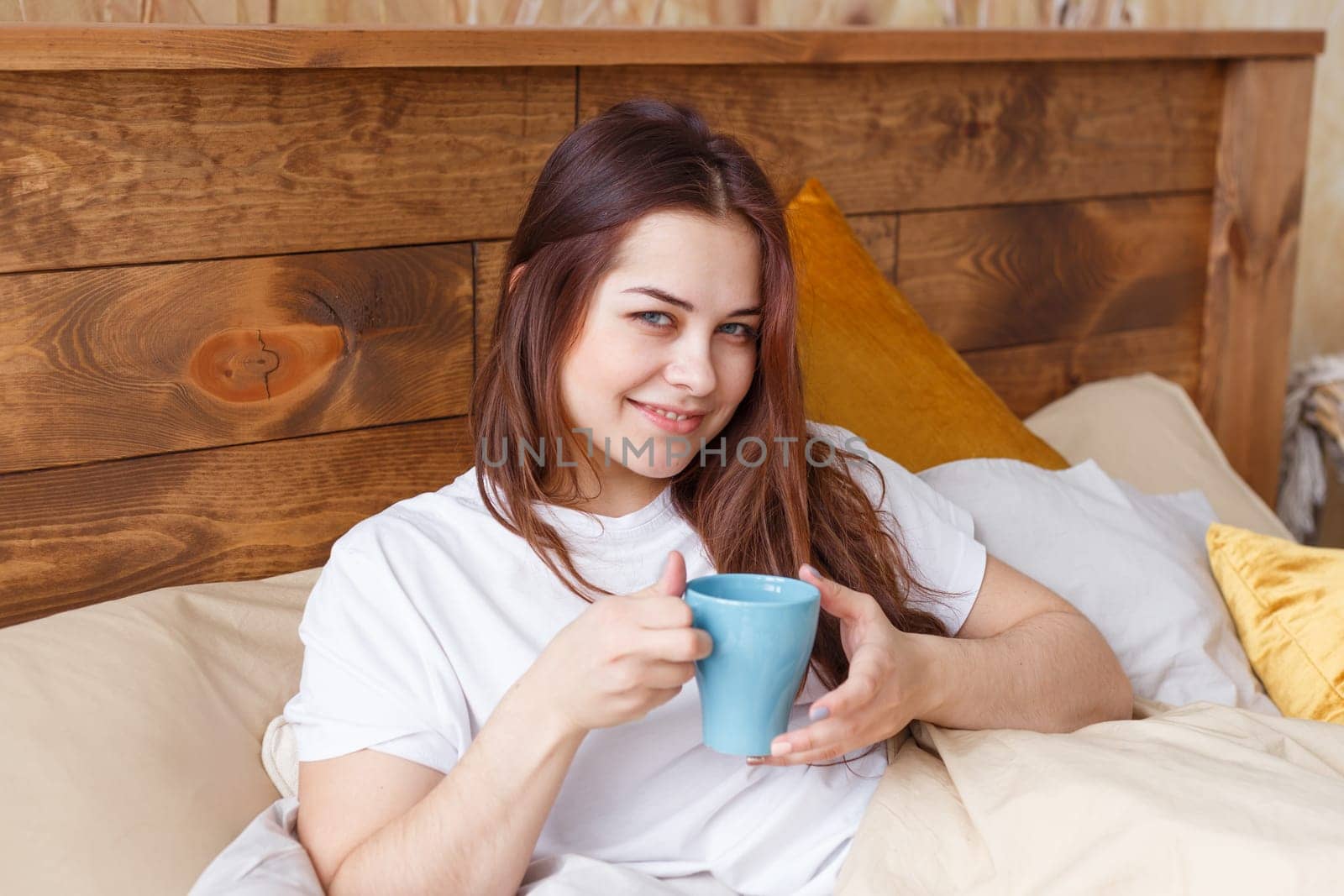 Happy woman awaking with cup of coffee at bedroom