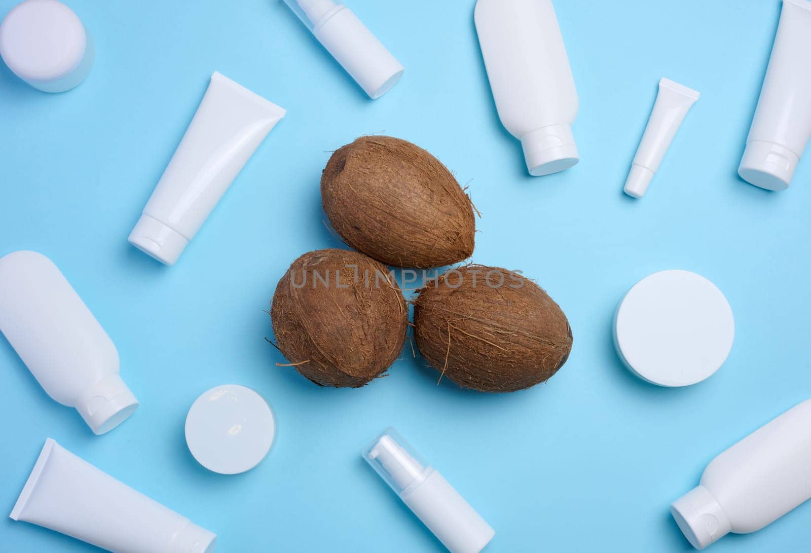 White plastic tubes, jars, and containers for cosmetic products on a blue background, advertising and branding of products