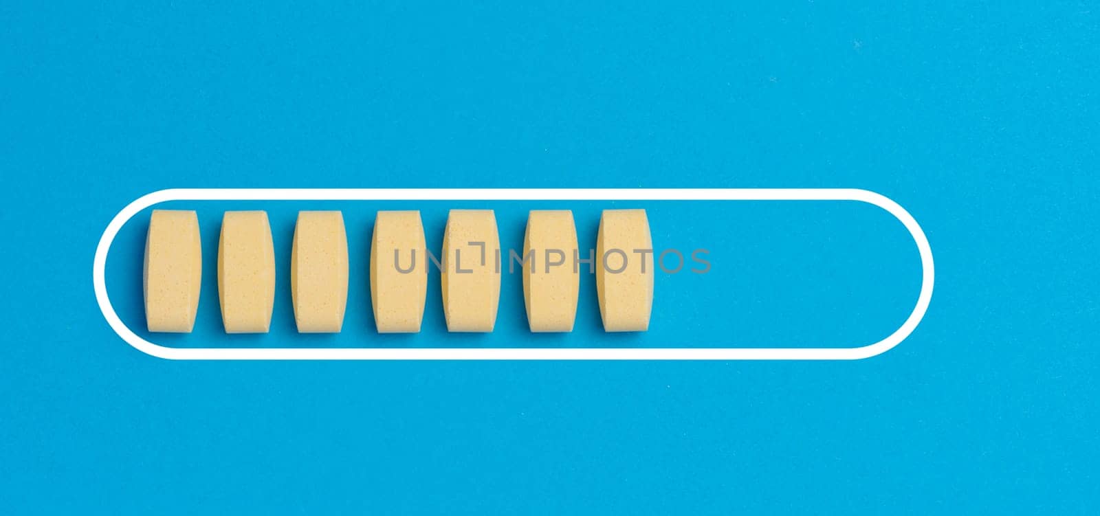 Yellow oval tablets on a blue background, top view