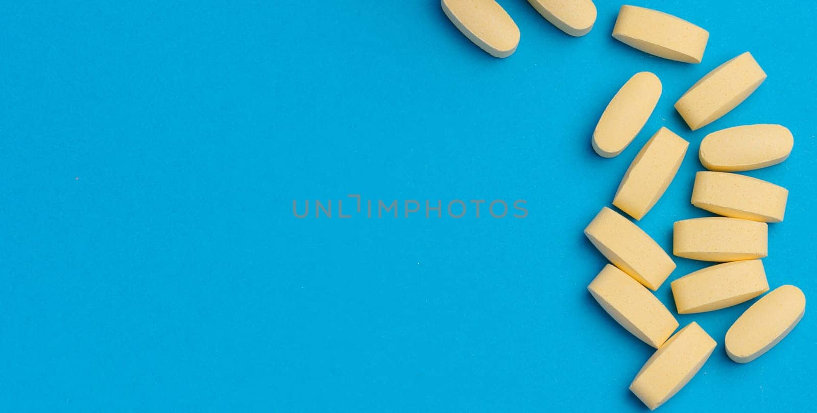 Yellow oval tablets on a blue background, top view. Copy space