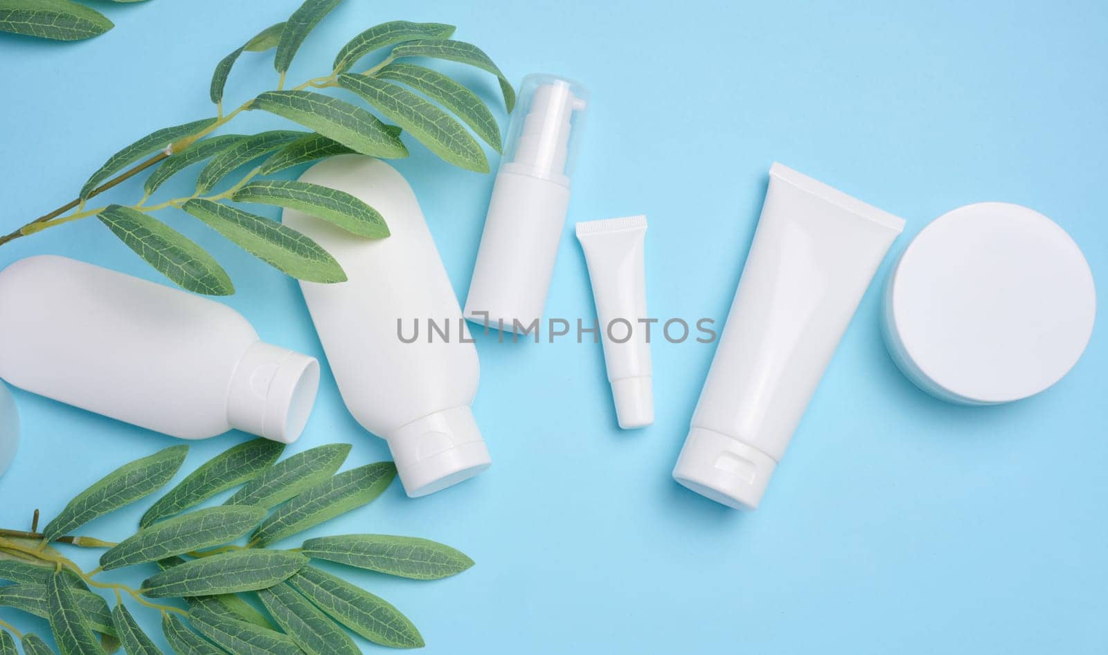 White plastic tubes, jars, and containers for cosmetic products on a blue background, advertising and branding of products