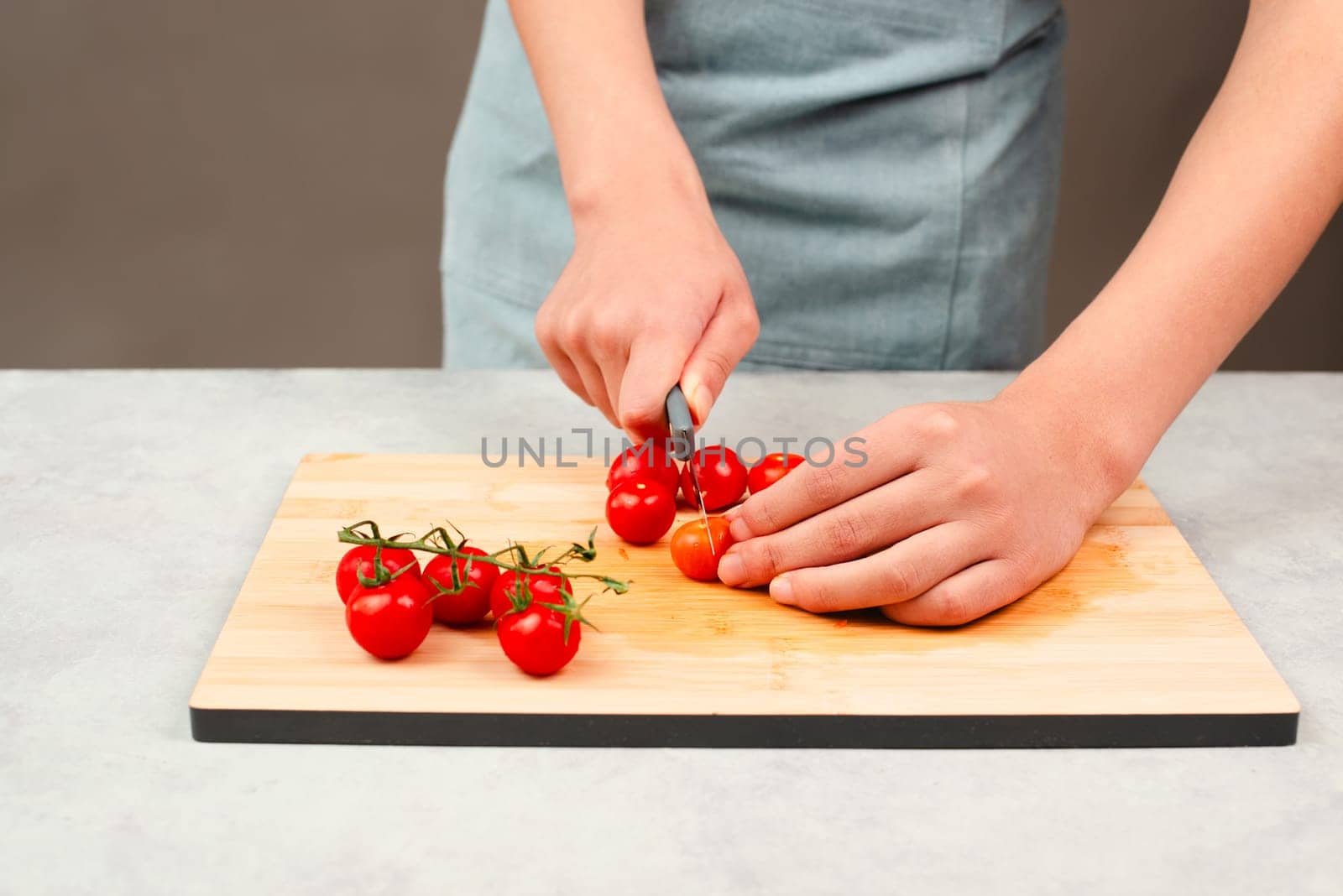 Cutting tomato on a wooden board, prepare salad, healthy food with vegetables, fresh organic nutrition, cooking ingredients