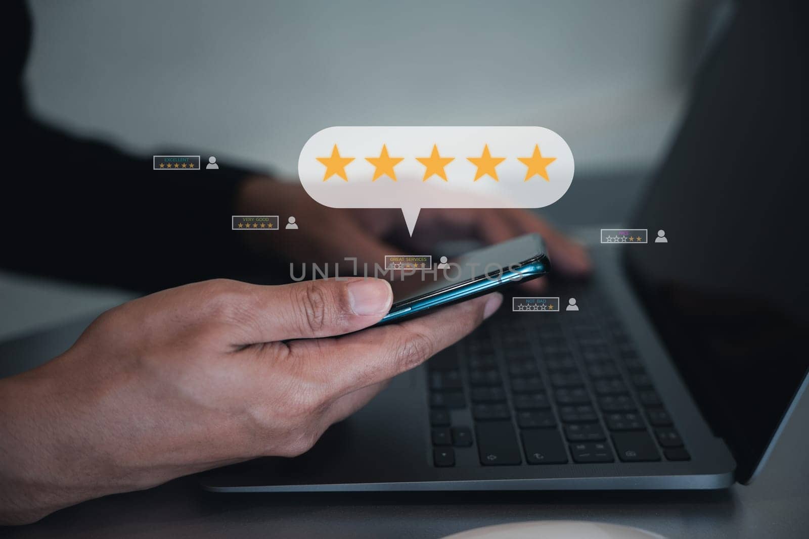 Man using smartphone and laptop computer to rate and evaluate services, with a popup five star icon for good feedback review. Business and technology concept with digital marketing