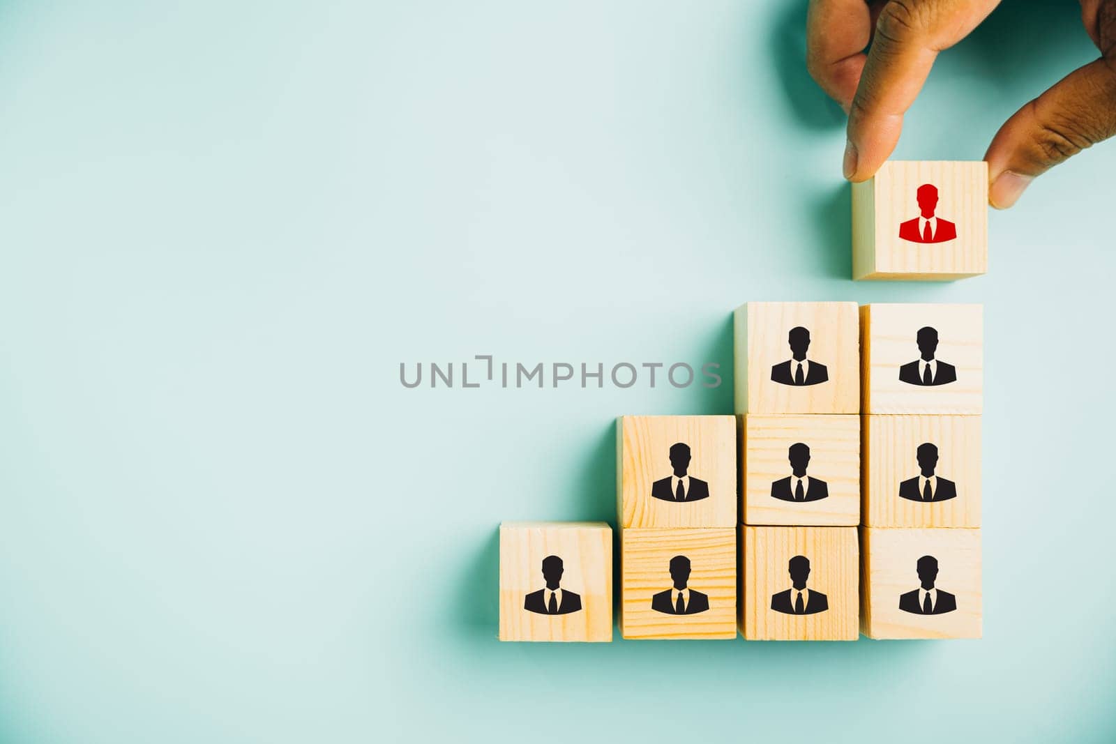 Conceptual stock photo depicting human resources talent management and recruitment. Person icons on wooden cube block symbolize teamwork and organization. Woman exemplifies leadership in business.