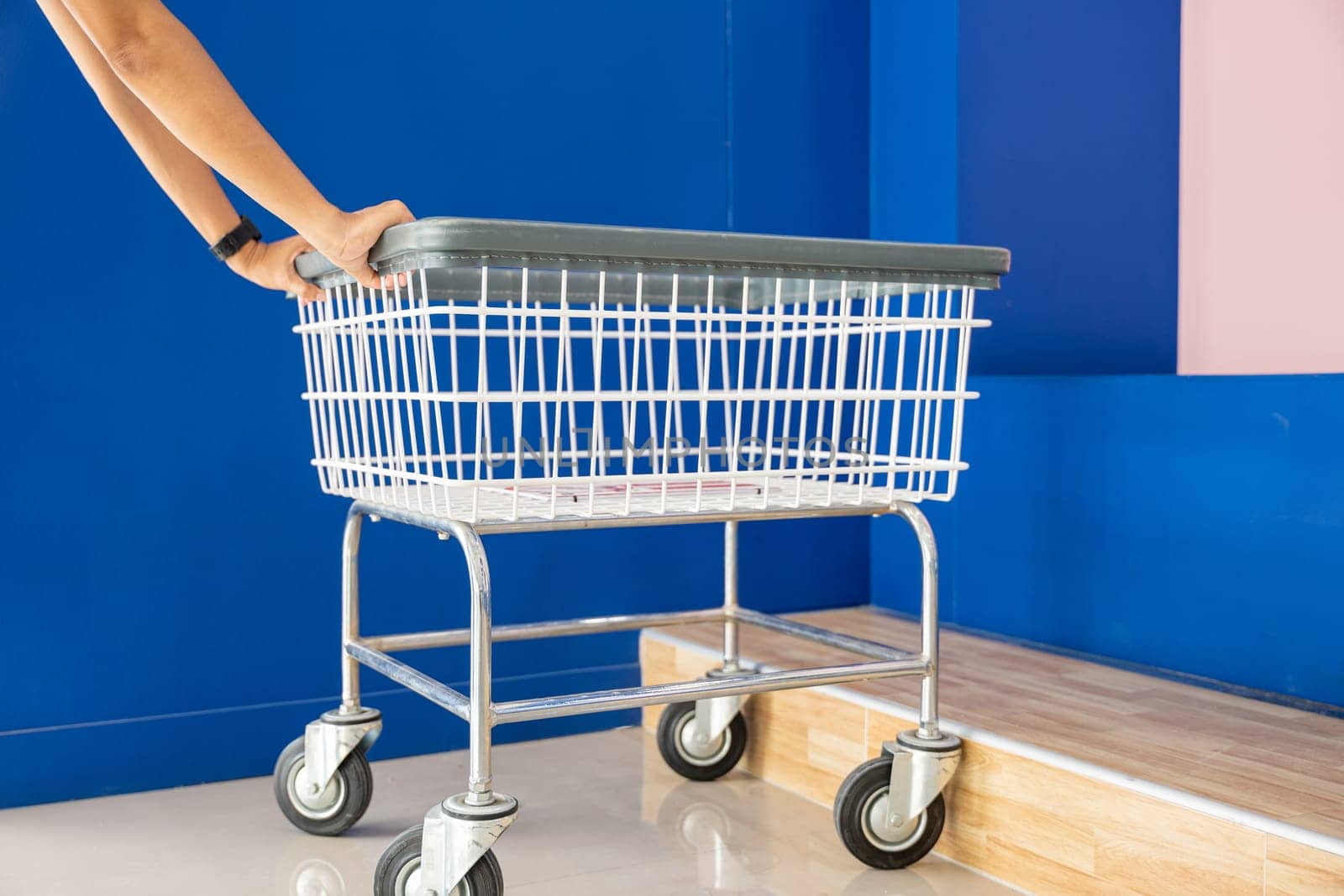 Laundry and housework. metal cart parked use for laundry at convenience store for support customer, Woman hands holding shove empty new white trolley cart, Laundromat convenience store concept