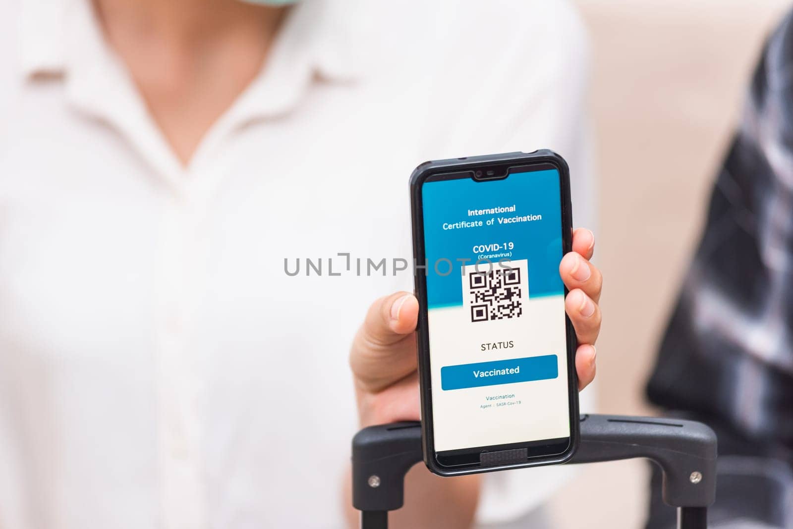 Young woman ready to travel showing digital vaccine health passport certificate app in smartphone screen during coronavirus pandemic, Mobile app of virus COVID-19 vaccination