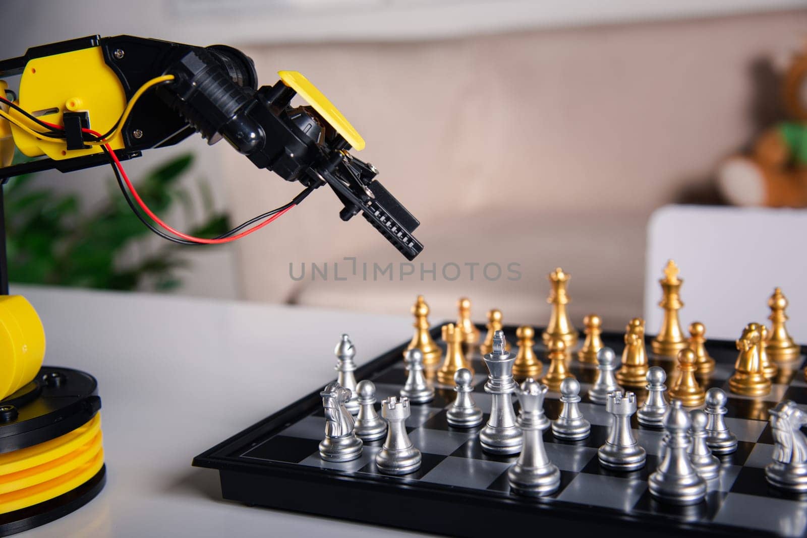 Closeup yellow robot arm playing move chess on chessboard, STEM education E-learning, Technology science robot education concept