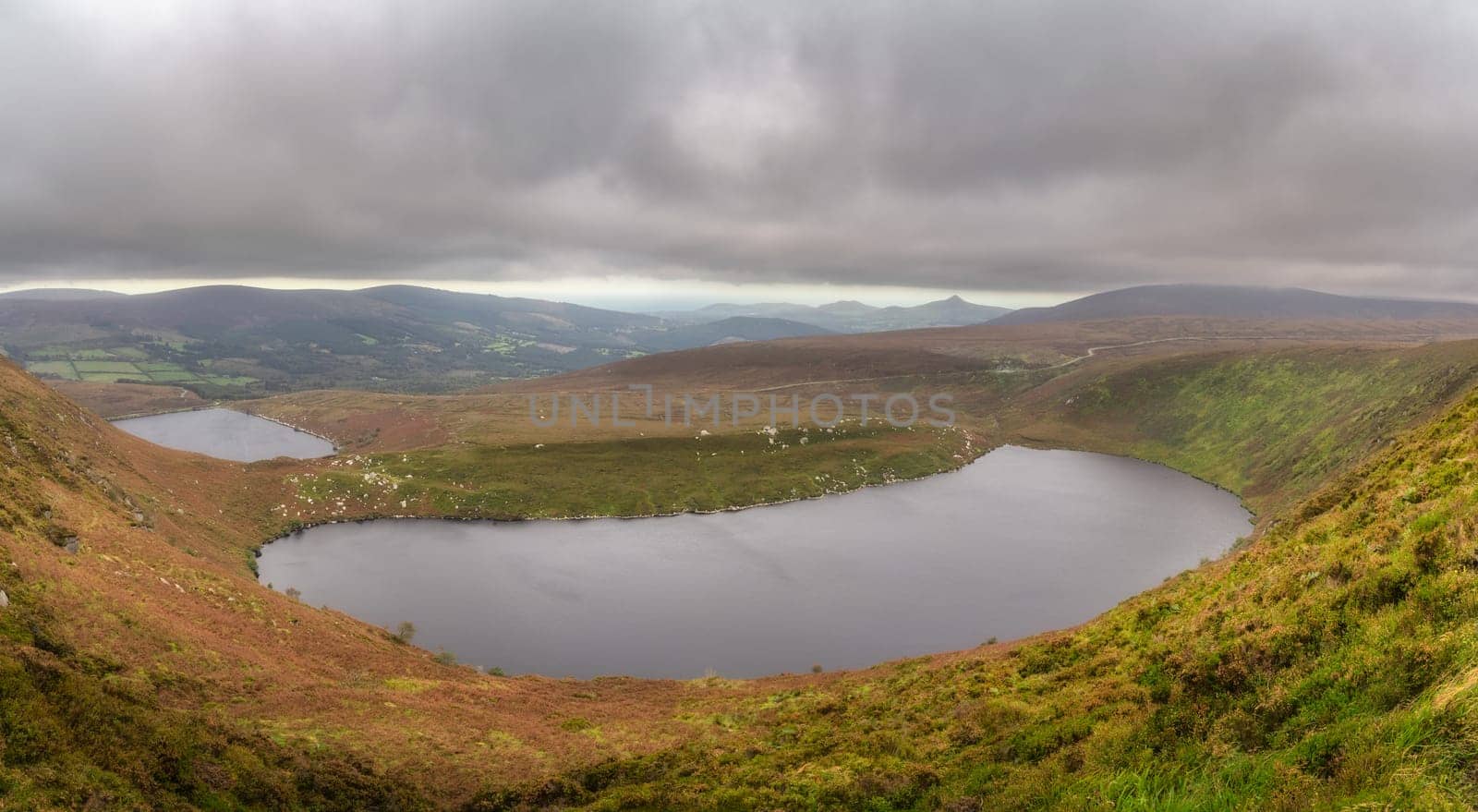 Panoramic view on upper and lower lakes Lough Bray, Sugarloaf and mountain range. Moody, dramatic storm clouds in Wicklow Mountains, Ireland