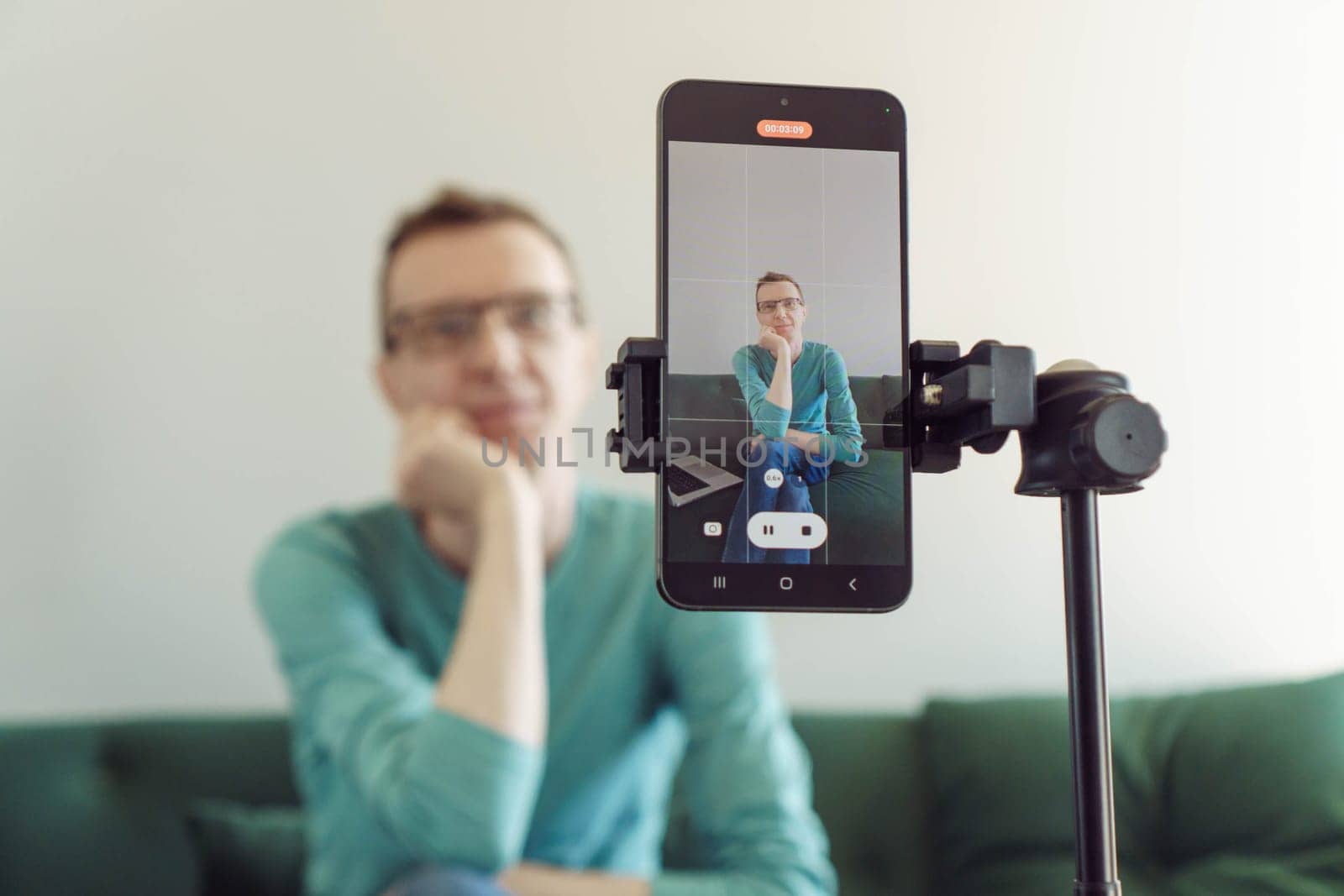 Blogging. In foreground is phone screen mounted on tripod with image from camera of male blogger recording his video. Modern technologies. Online training. Video recording of trainings.