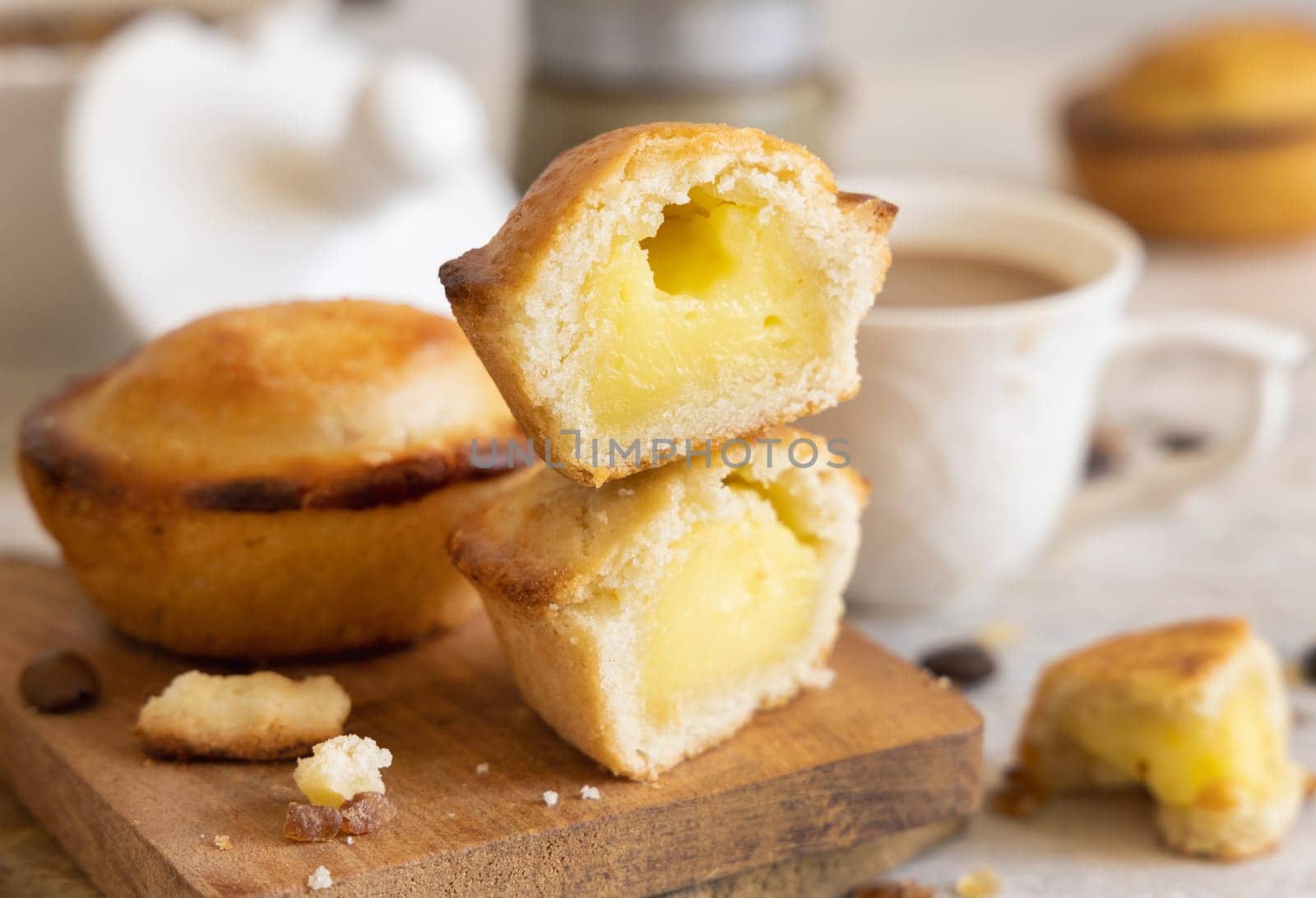 Pasticciotto leccese pastry filled with egg custard cream, typical sweet from Lecce, Italy. Pieces of pasticiotto on a wooden board, apulian breakfast with coffee prepared, close up