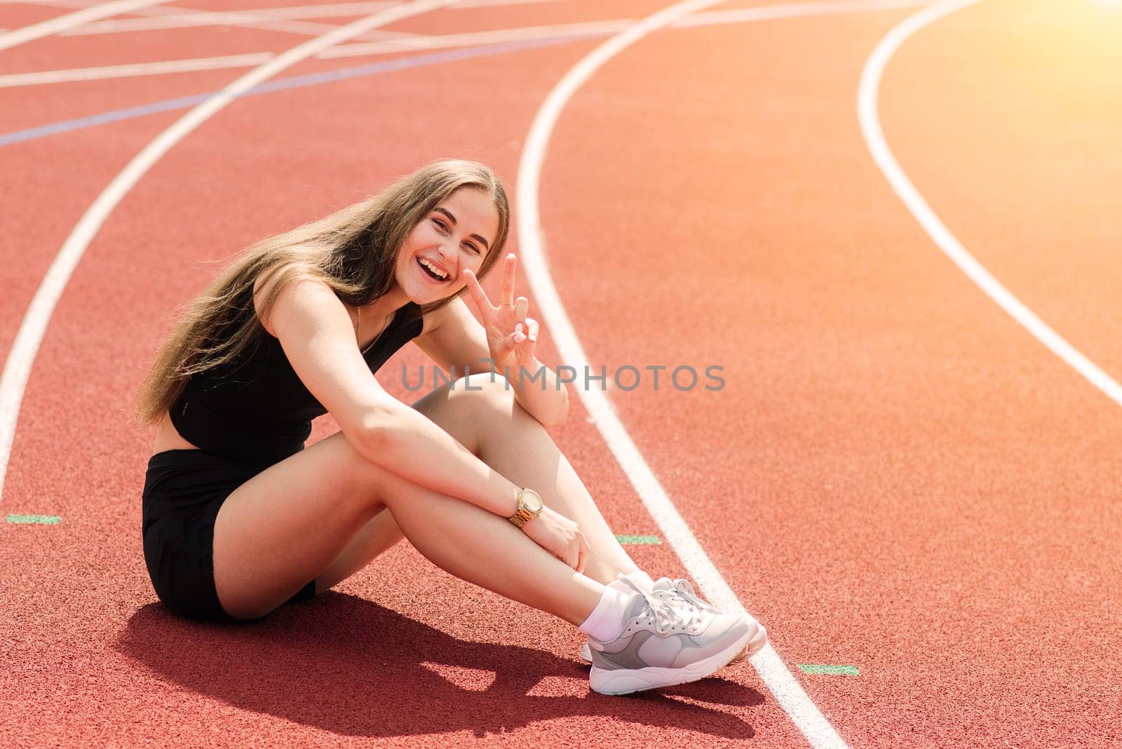 Young, beautiful girl athlete in sportswear is training and running, stretching at the stadium