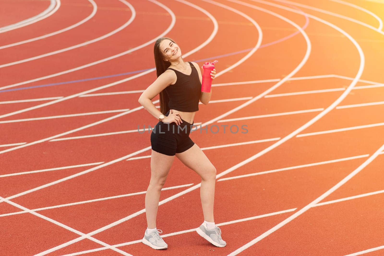 Young, beautiful girl athlete in sportswear is training and running, stretching at the stadium
