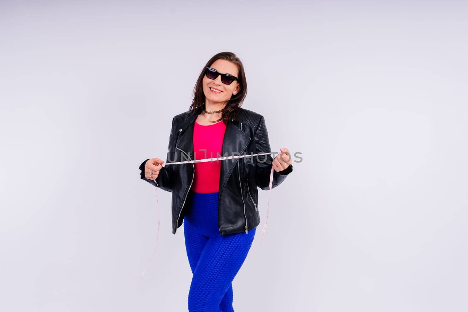 Overweight woman measuring waist before weight loss in a studio shot on yellow background