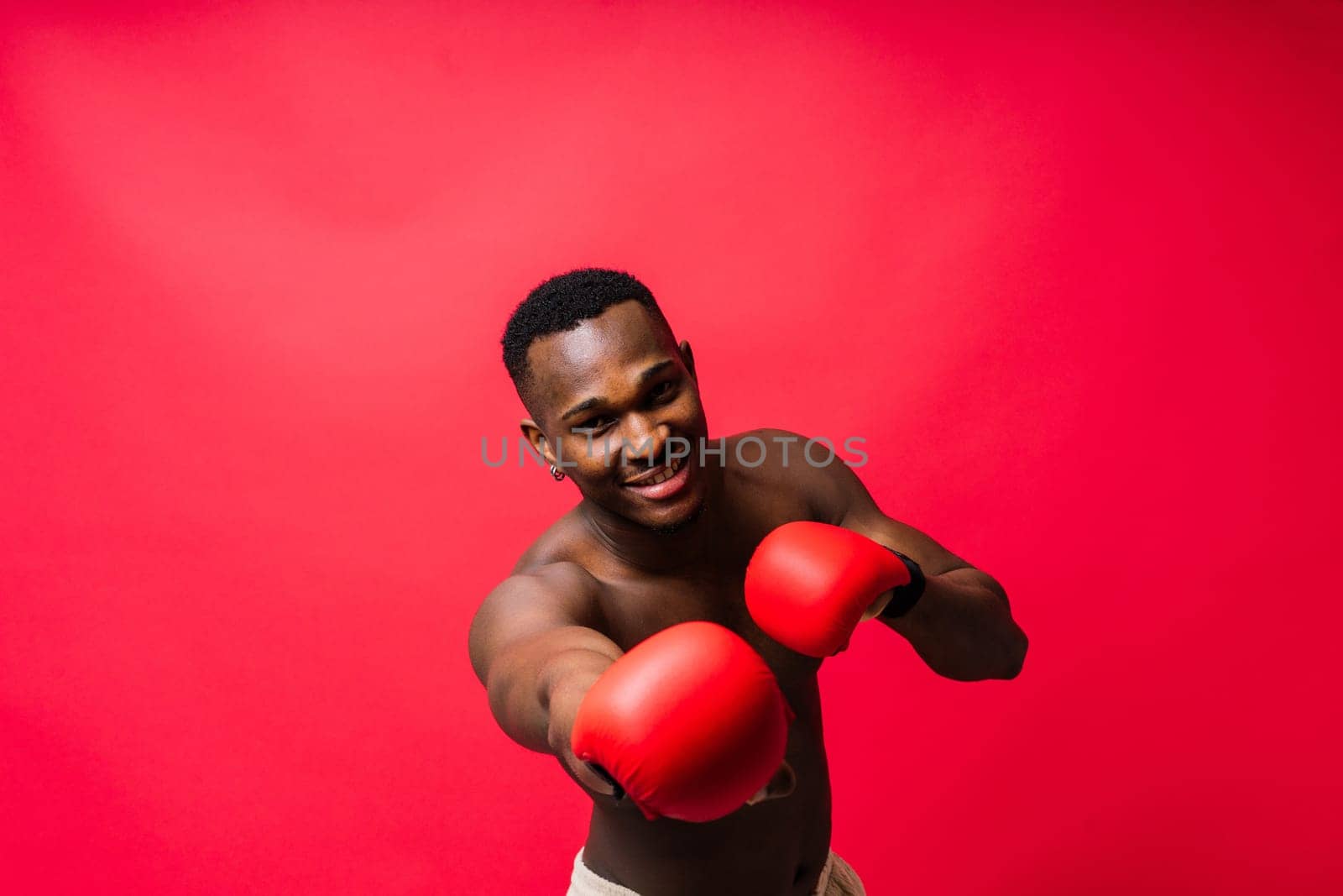 Muscular serious looking african boxer training, in studio red background