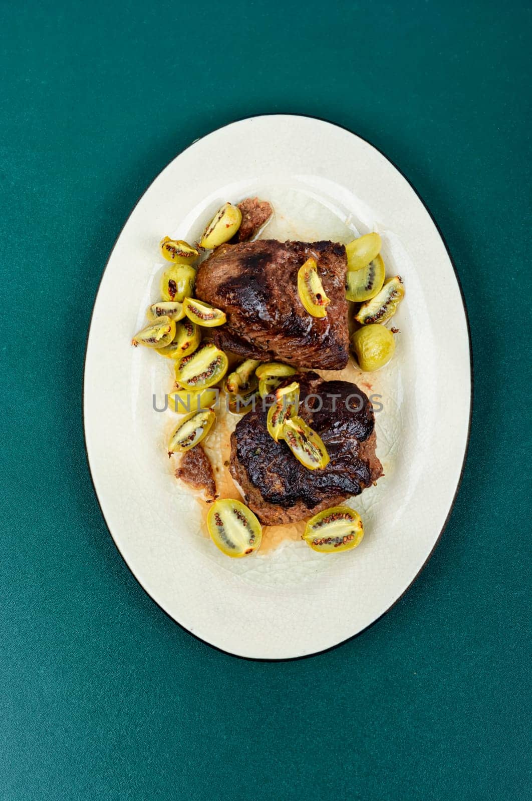 Roasted ostrich steak and mini kiwi on a plate