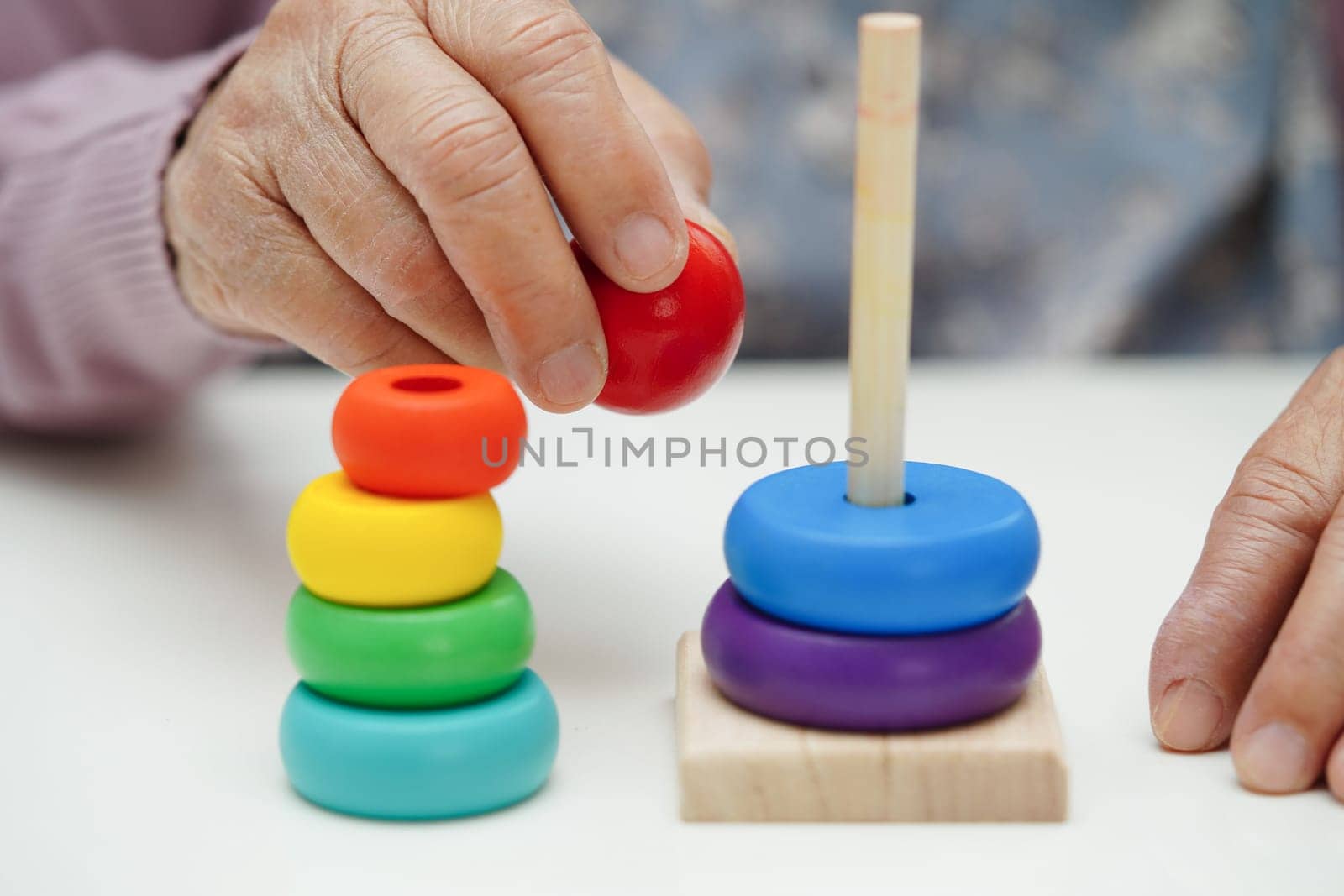 Asian elderly woman playing puzzles game to practice brain training for dementia prevention, Alzheimer disease.