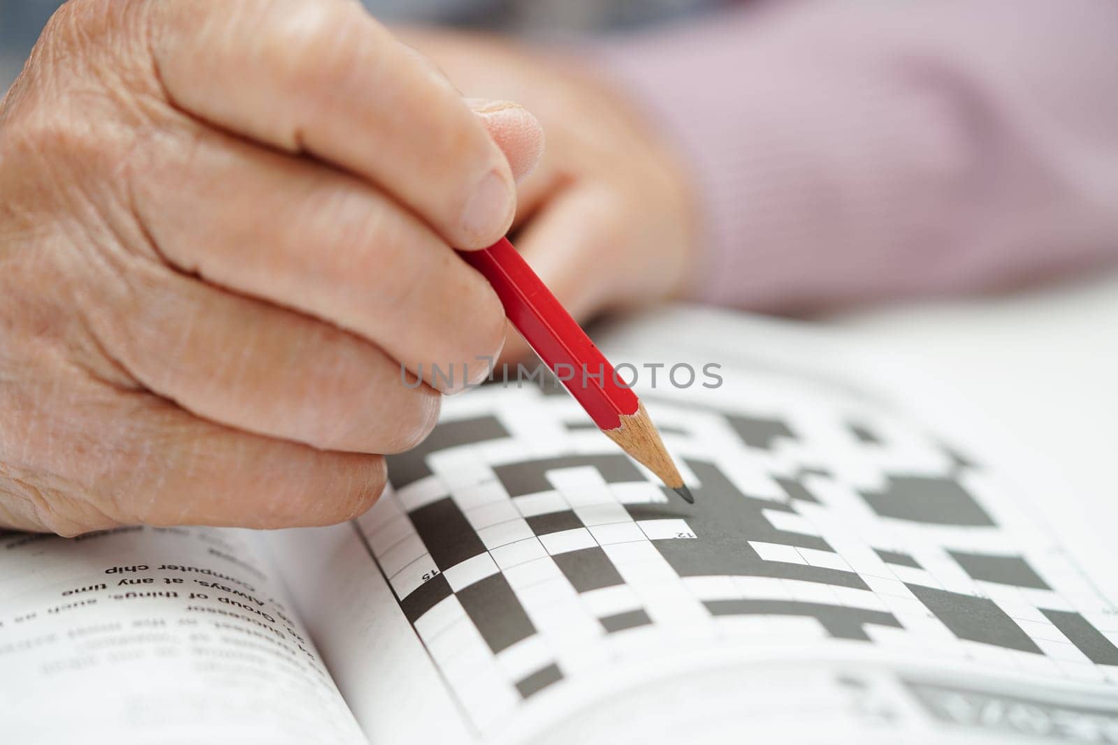 Asian elderly woman playing sudoku puzzle game to practice brain training for dementia prevention, Alzheimer disease.