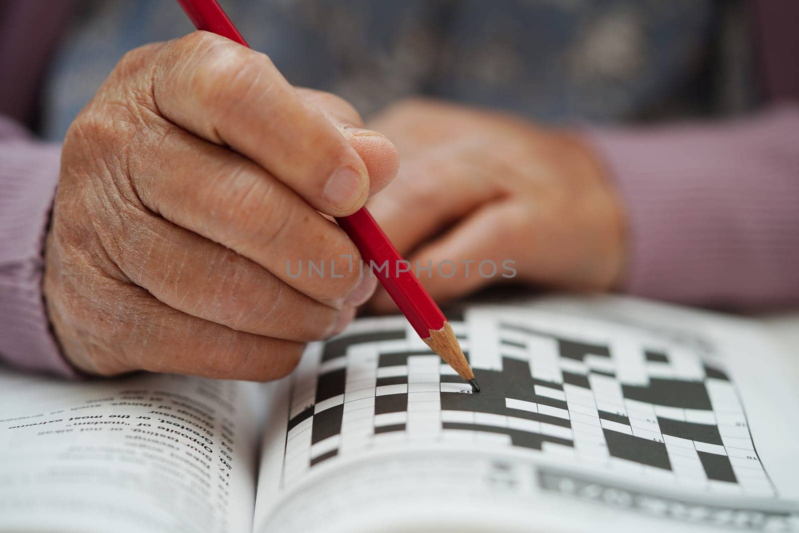 Asian elderly woman playing sudoku puzzle game to practice brain training for dementia prevention, Alzheimer disease.