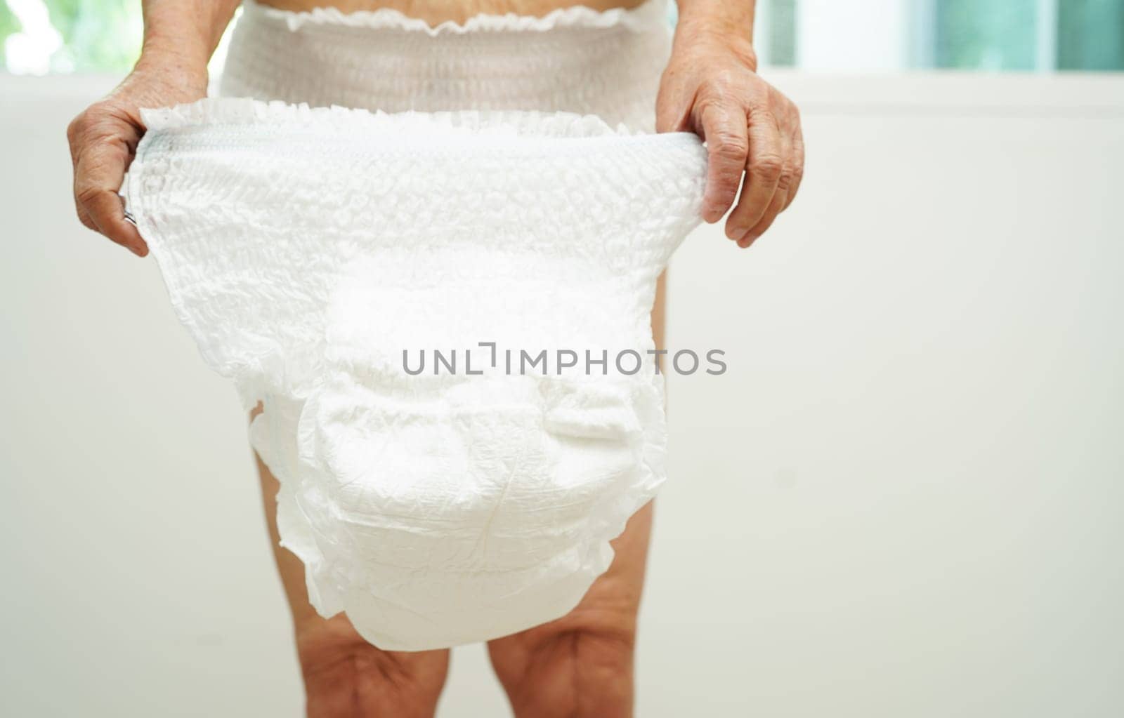 Asian senior woman patient wearing adult incontinence diaper pad in hospital.