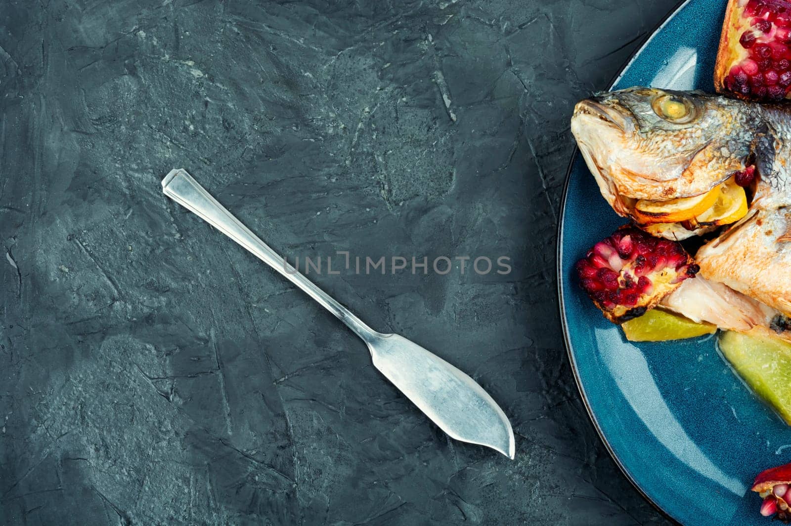 Tasty baked dorado fish with melon and pomegranate. Space for text.