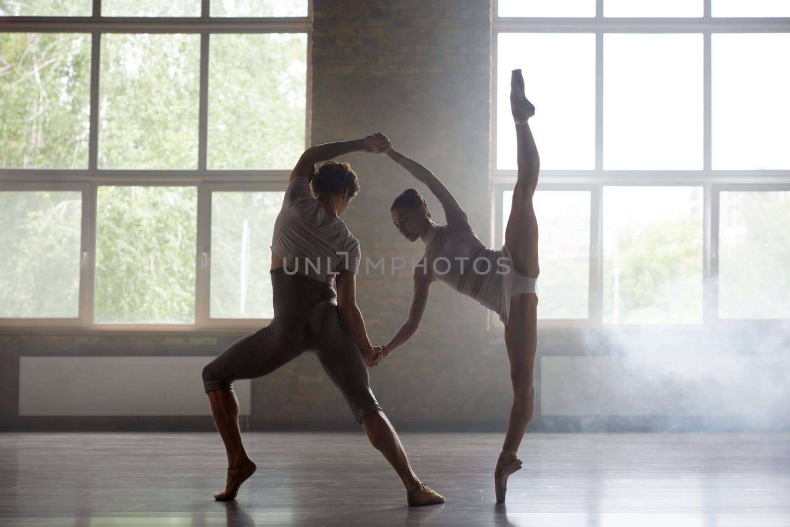 Man and woman ballet dancers performing together against studio background. Contemporary choreography performance