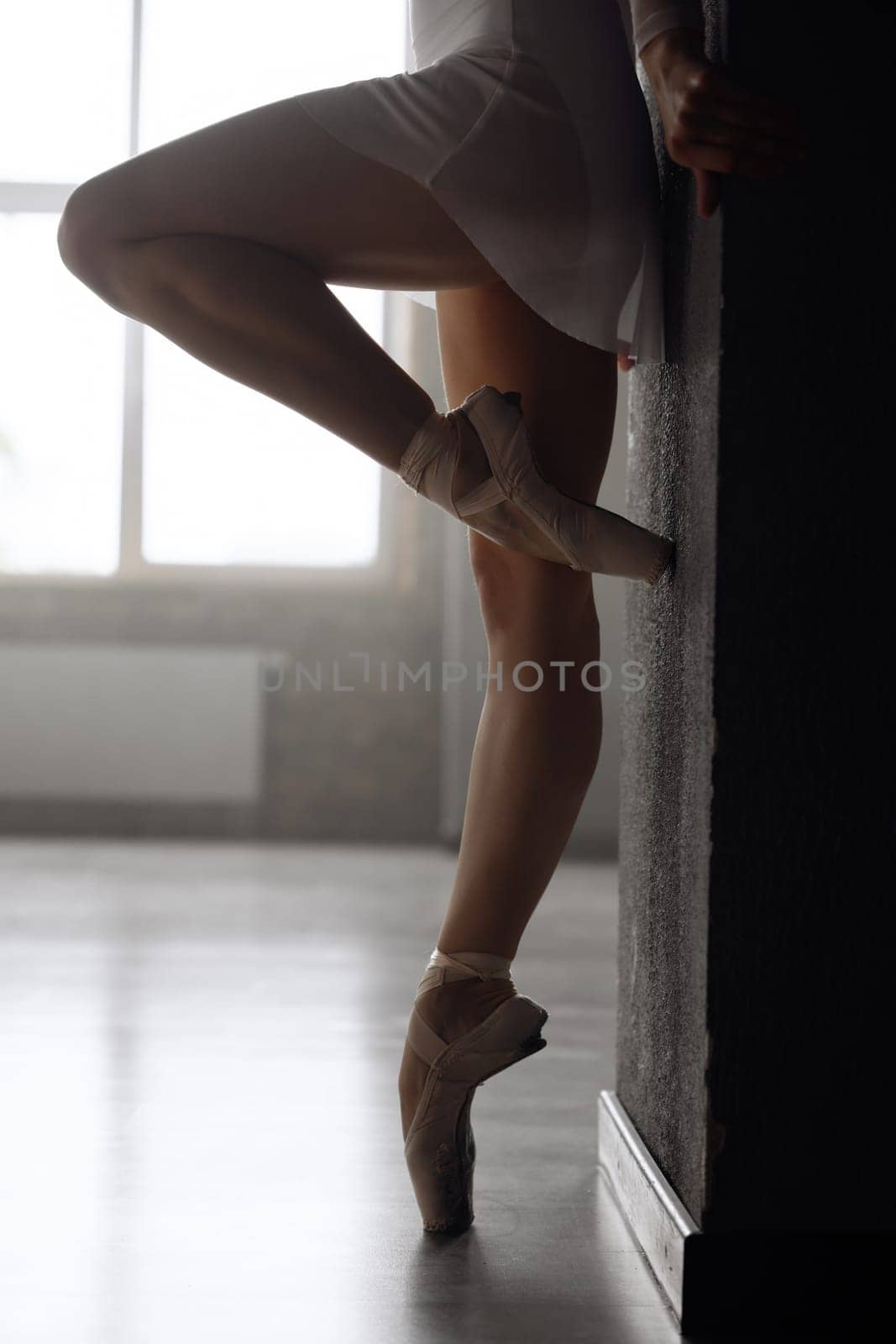 Closeup view on legs of young ballerina wearing pointe shoes. Classical ballet practice at dance school