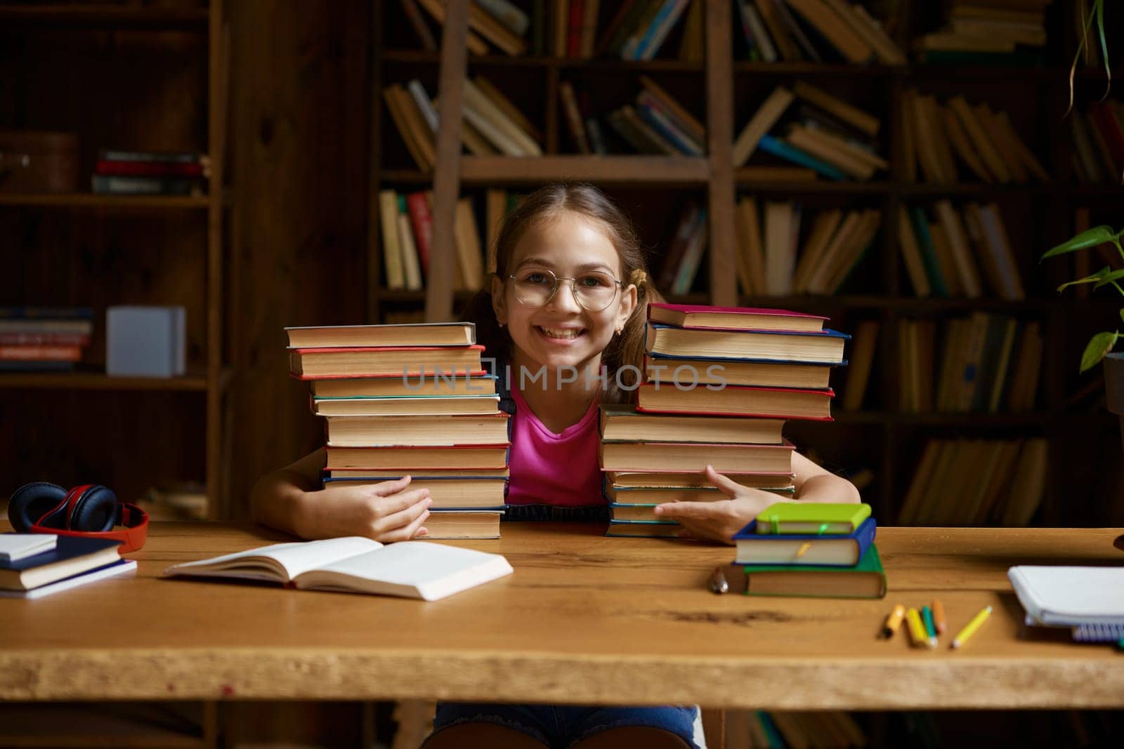Back to school concept. Happy little schoolgirl leaning on stack on textbooks ready to study hard on remote lessons of virtual classroom platform