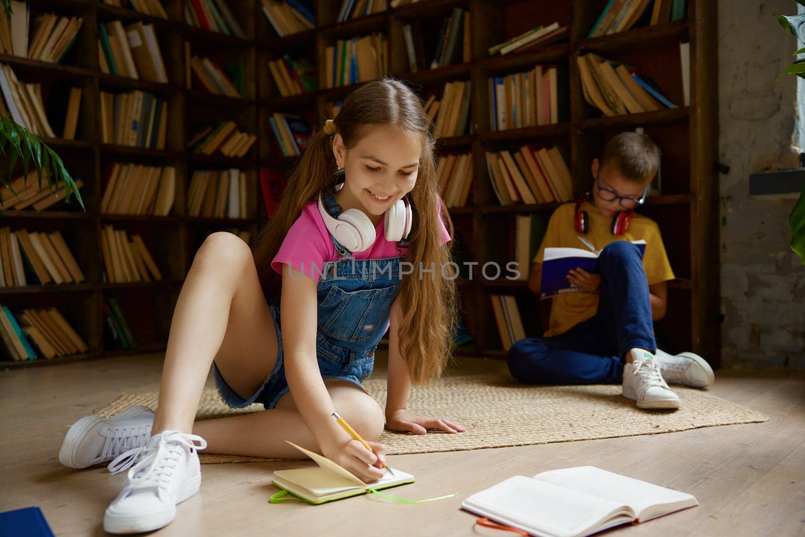 Little schoolchildren spending time at home library. Brother and sister doing homework, having nice pastime during break in day of education