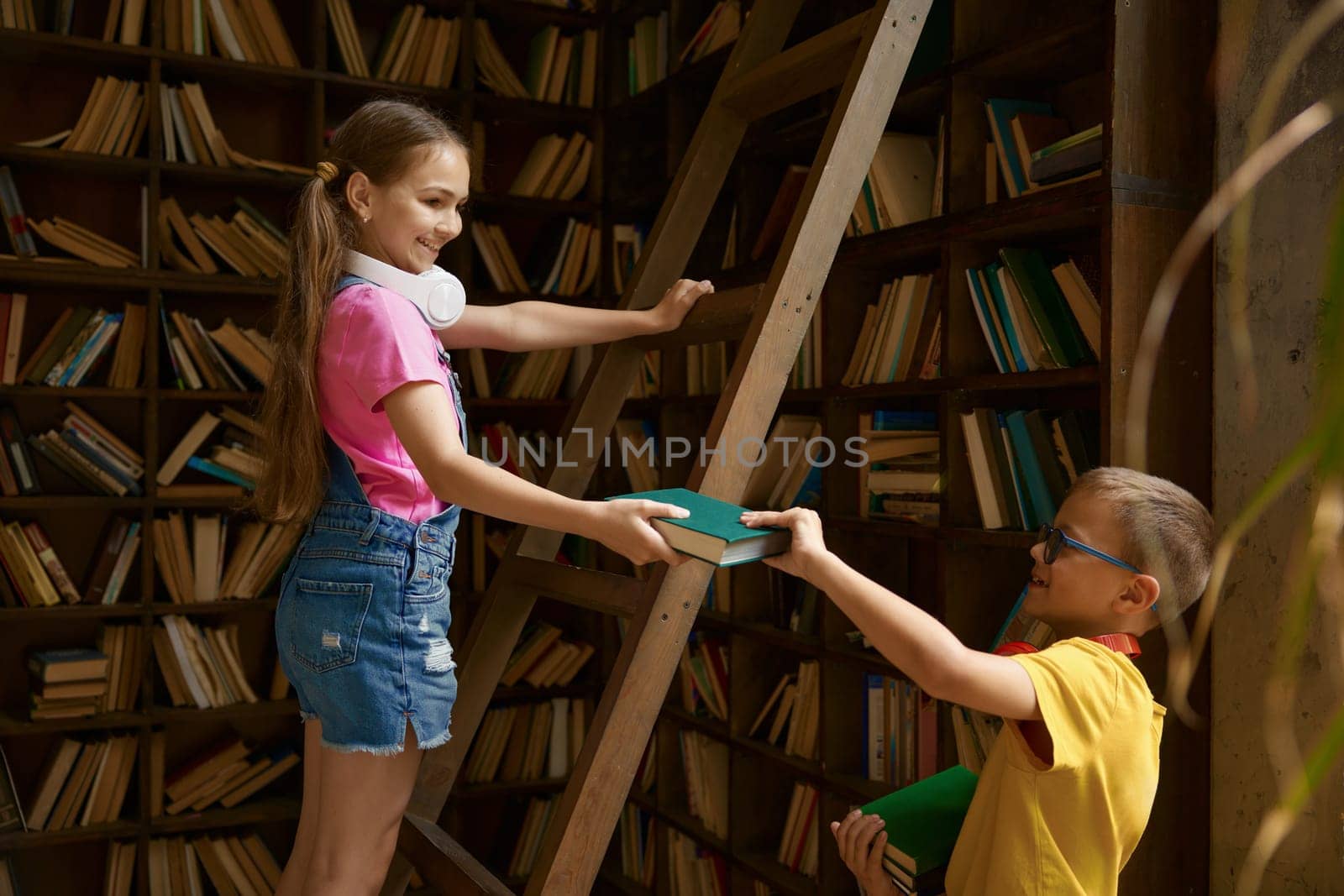 Children being on duty putting away books in home or school library. Family relationships between siblings or schoolkid nice behavior