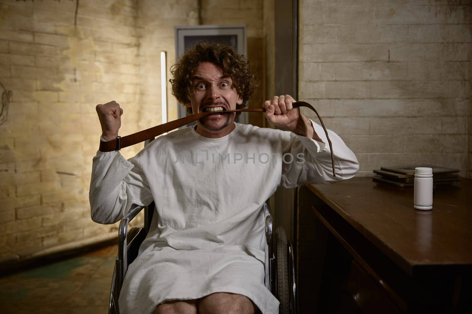 Mad man patient biting leather belt at doctor appointment showing deterioration of condition and lack of positive dynamics in treatment of schizophrenia