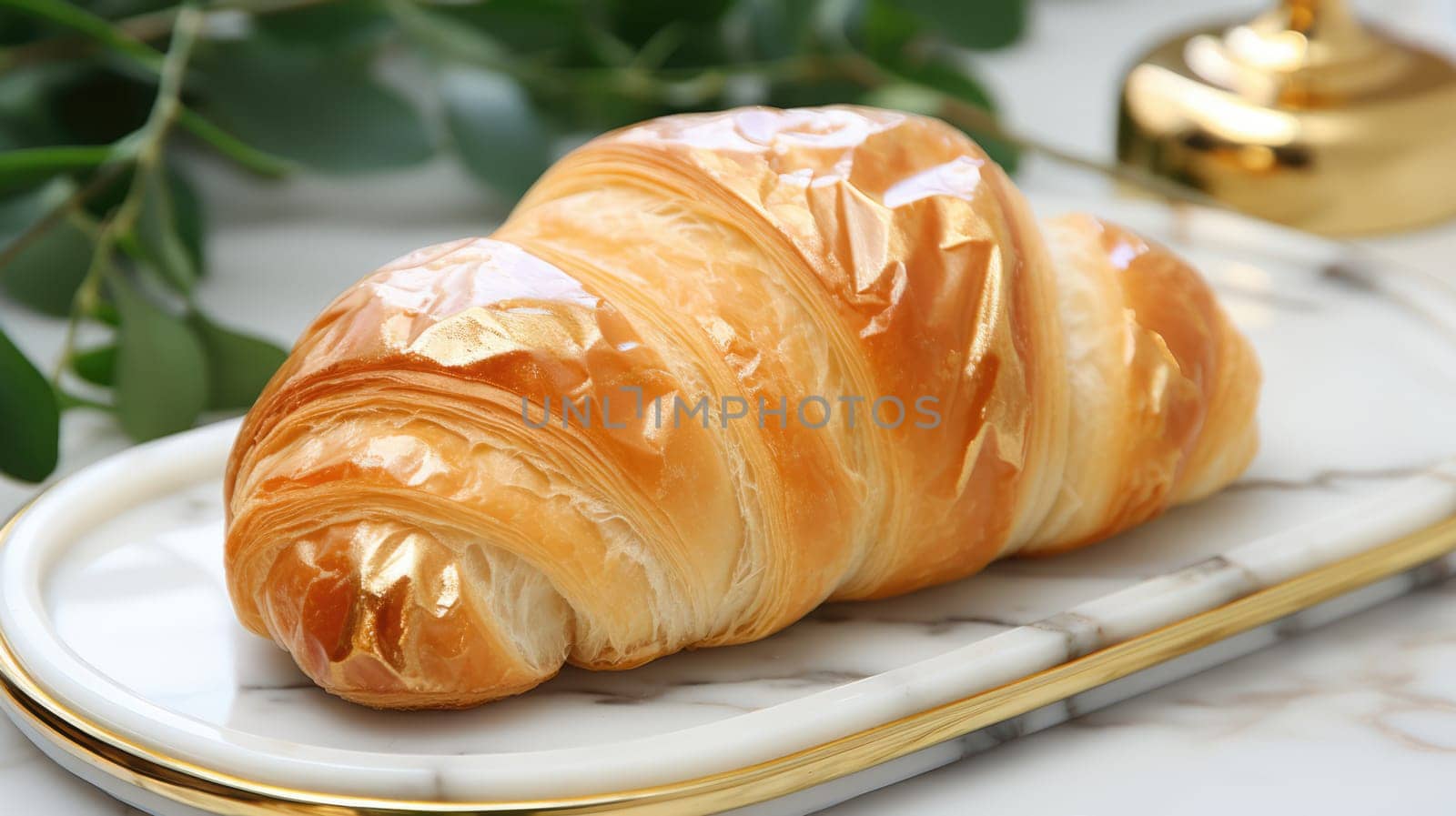 freshly baked croissant with butter served on a white plate on a marble table with flowers on a sunny morning