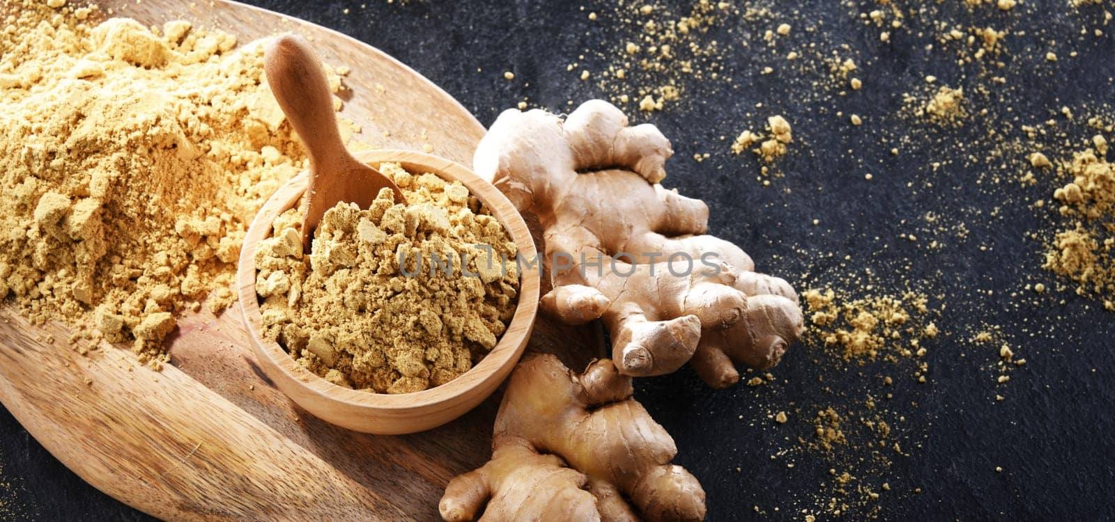 A bowl with ground ginger and its fresh rhizome.