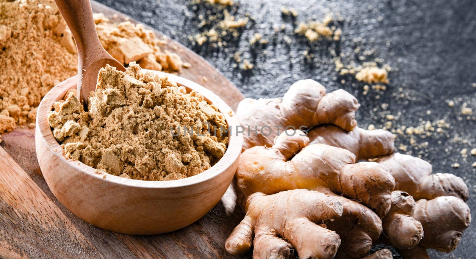 A bowl with ground ginger and its fresh rhizome.