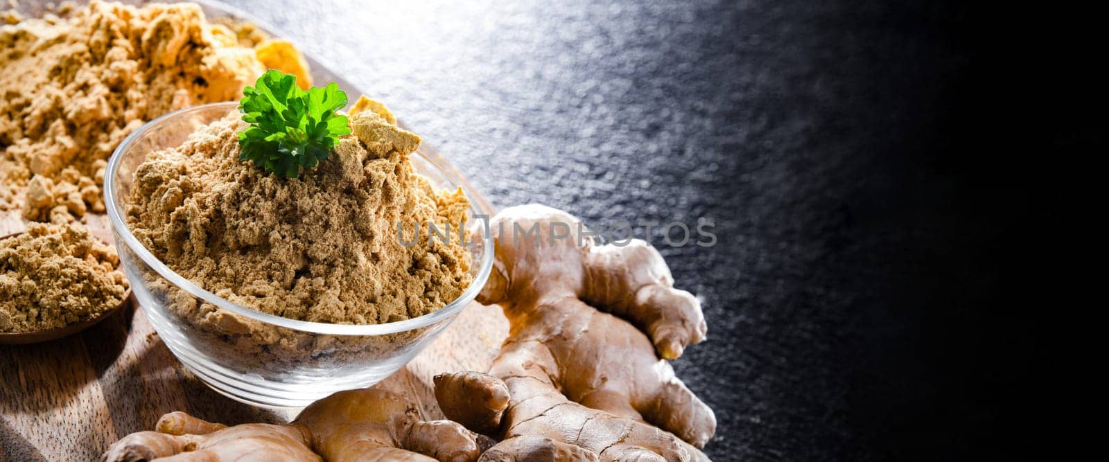 A bowl with ground ginger and its fresh rhizome.