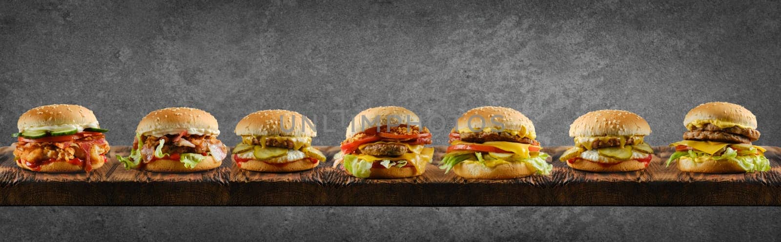 Assortment of different types of burgers on long wooden board
