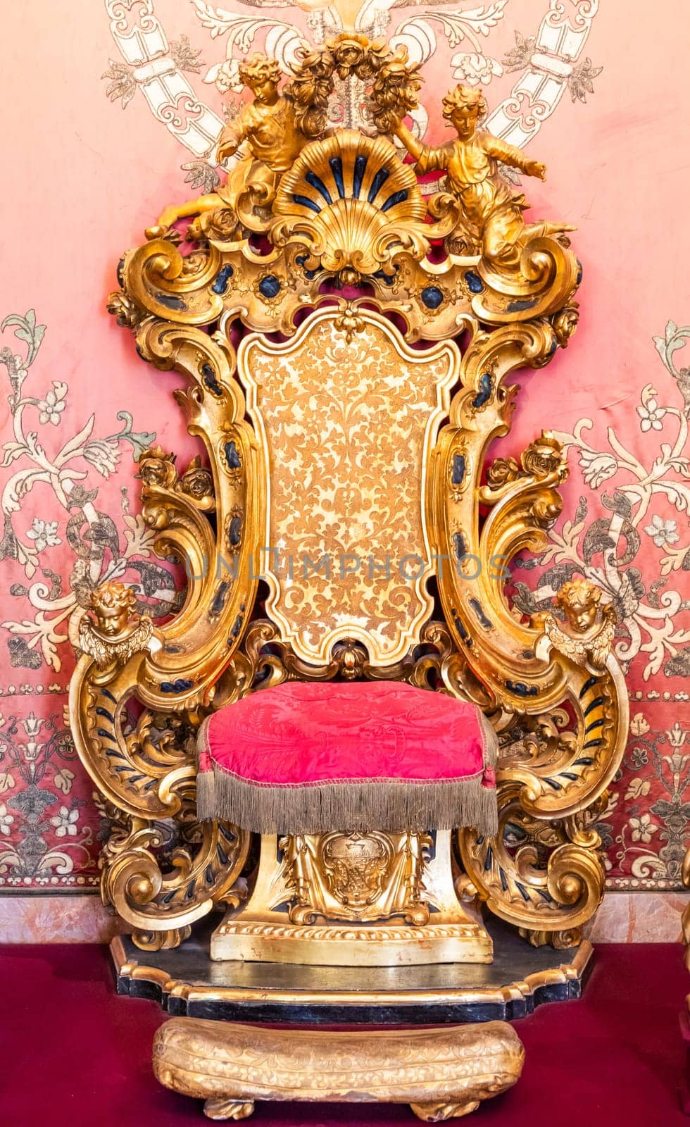 Isola Bella, Italy - 1 August 2023: antique throne in gold and red velvet. Old royal chair, luxury vintage.